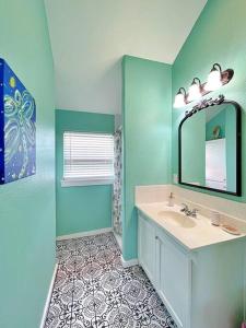 a blue bathroom with a sink and a mirror at The Pink Flamingo Beach Gulf views in Freeport
