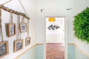 a hallway with pictures on the wall and a door with a plant at Goa Square by Lisbon with Sintra in Amadora