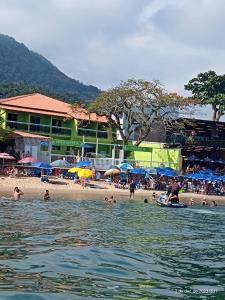 un grupo de personas en una playa con sombrillas en Pousada e Restaurante J L . en Mangaratiba