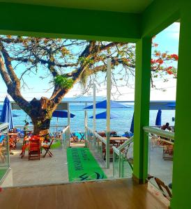 una terraza con un árbol y vistas al océano en Pousada e Restaurante J L ., en Mangaratiba