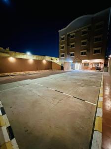 an empty parking lot in front of a building at night at المهيدب للشقق المخدومة in Al Fuḑūl