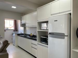a kitchen with white cabinets and a refrigerator at Residencial Helena in Porto Belo