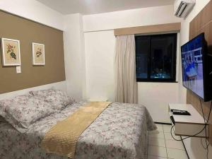 1 dormitorio con 1 cama, TV y ventana en Flat Biarritz em São Luís com excelente localização! en São Luís