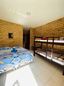 1 Schlafzimmer mit 2 Etagenbetten und Ziegelwand in der Unterkunft Casa do Ric in Caucaia