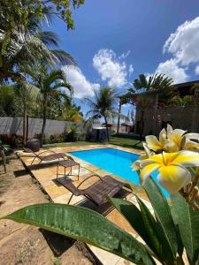 einem Pool mit Stühlen und einer gelben Blume in der Unterkunft Casa do Ric in Caucaia
