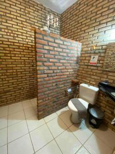 ein Bad mit einem WC und einer Ziegelwand in der Unterkunft Casa do Ric in Caucaia