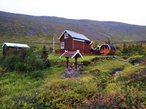 un granero y una casa en un campo en Valhöll Skátaskáli, en Ísafjörður