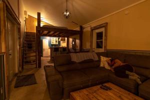 a woman laying on a couch in a living room at Tiny house & Sauna on Lakefront Farm Oasis in Merville