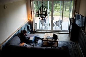 a woman sitting on a couch reading a book at Tiny house & Sauna on Lakefront Farm Oasis in Merville