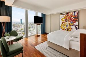 um quarto de hotel com uma cama e uma grande janela em JW Marriott Hotel Frankfurt em Frankfurt am Main