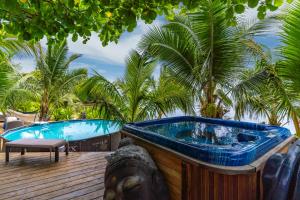 une baignoire jacuzzi sur une terrasse avec des palmiers dans l'établissement Fare Oaoa Haapiti, à Moorea