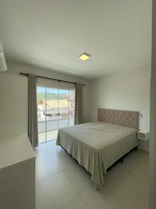 a bedroom with a bed and a large window at Residencial Helena in Porto Belo