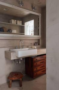 a bathroom with a sink and a mirror and a stool at Apartamento único no coração do Jardim Botânico in Rio de Janeiro