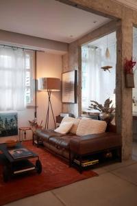 un soggiorno con divano in pelle in una camera di Apartamento único no coração do Jardim Botânico a Rio de Janeiro