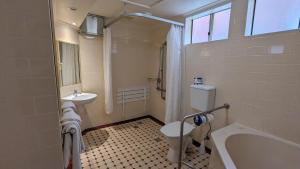 a bathroom with a tub and a toilet and a sink at River Motel in Queanbeyan