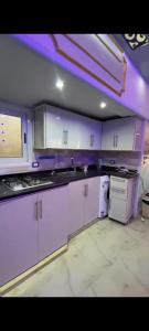 a kitchen with white cabinets and purple lighting at Sea View Studio alexandria in Alexandria