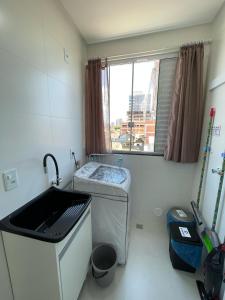 a small kitchen with a sink and a window at Residencial Helena Perequê Porto Belo SC in Porto Belo