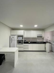 a kitchen with white cabinets and a white table at Residencial Helena Perequê Porto Belo SC in Porto Belo
