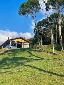 uma casa no topo de uma colina relvada com árvores em Cabana Santo Reffúgio em Urubici