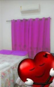 POUSADA CASA AMARELA في شابادا دوس غيماريش: وجود قلب احمر كبير جالس امام سرير