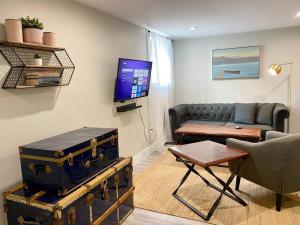 een woonkamer met een bank, een tv en een tafel bij Hidden Getaway, BSMT with Back Yard in Halifax