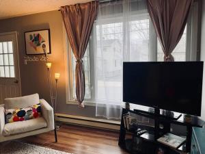 ハリファックスにあるCozy 2-BDRM, Mid Floor, Backyardの薄型テレビと椅子のあるリビングルーム