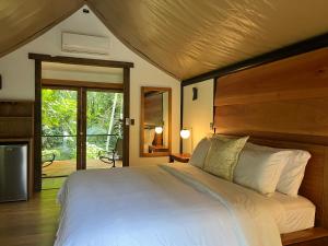 a bedroom with a large white bed with a wooden headboard at Hotel Arenal Glamping in Fortuna