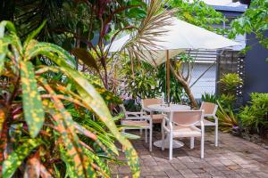 un patio con mesa, sillas y sombrilla en Cairns City Backpackers Hostel en Cairns