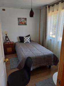 a bedroom with a bed and a chair in it at CABAÑAS LOMAS DE YECO in Valdivia