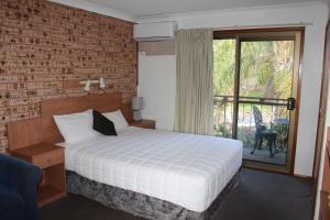 a bedroom with a bed and a brick wall at Bridge View Motel in Gorokan