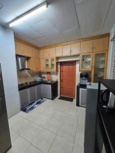 uma cozinha com armários de madeira e uma porta vermelha em Ruhani Homestay 3 KB - 4 Bedroom Fully Airconditioned with WIFI & Netflix em Kota Bharu