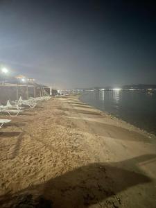 una spiaggia con sedie bianche e acqua di notte di Elpiniki Luxury Apartments a Nea Potidaea