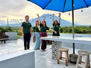 Un groupe de personnes debout à côté d'une table avec un parapluie dans l'établissement Khrisna Sunrise Homestay Tulamben, à Tulamben