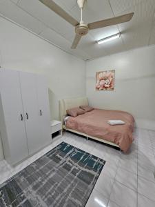 een slaapkamer met een bed en een plafondventilator bij Ruhani Homestay 3 KB - 4 Bedroom Fully Airconditioned with WIFI & Netflix in Kota Bharu