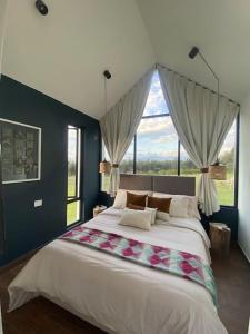 a large bedroom with a large bed with windows at Casa con vista a las montañas in Quito