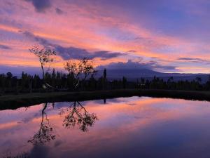 una puesta de sol con un reflejo en un estanque en Casa con vista a las montañas en Quito