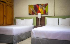 two beds sitting next to each other in a hotel room at Suites del Sol Hotel & Apartments in Mérida
