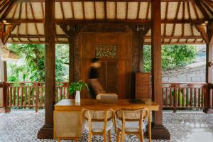 Sanubari Ubud في أوبود: طاولة وكراسي في جناح مع شخص