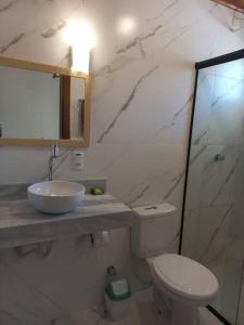 a bathroom with a toilet and a sink and a mirror at Recanto das Acacias in Balneário Camboriú