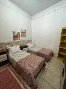a bedroom with two beds and a book shelf at Meu Quarto no Rio de Janeiro in Duque de Caxias