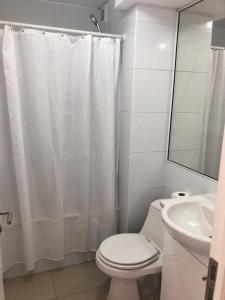 a white bathroom with a toilet and a sink at Condominio costazul La Herradura in Coquimbo