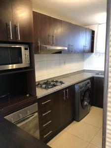 a kitchen with a stove and a microwave and a washer at Condominio costazul La Herradura in Coquimbo
