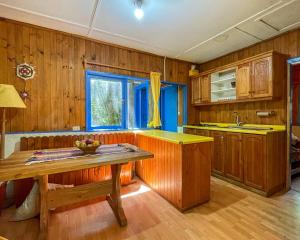 una cucina con armadi in legno e tavolo in legno di Casa con acceso directo al lago. a Caburgua