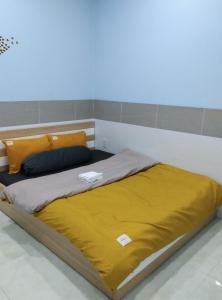 a bed with yellow sheets and pillows in a room at NHÀ NGHỈ ANA in Cái Răng
