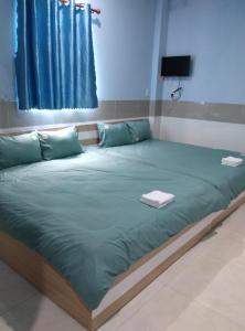 a large bed with green sheets in a room at NHÀ NGHỈ ANA in Cái Răng