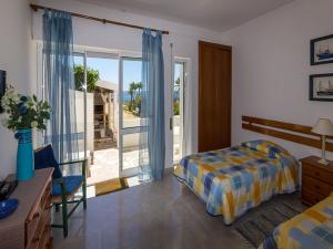 een slaapkamer met een bed en een glazen schuifdeur bij Alojamento Mareta in Sagres