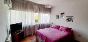 1 dormitorio con 1 cama, TV y ventana en Emilio Civit en Mendoza