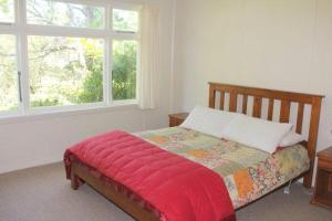 a bedroom with a bed with a red blanket and a window at 44 Scarborough Tce in Hanmer Springs
