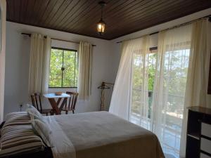 a bedroom with a bed and a table and windows at Recanto das Acacias in Balneário Camboriú