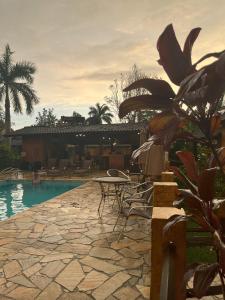 een terras met een tafel en stoelen naast een zwembad bij Camburi Chalés in Camburi